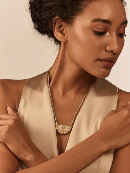 The Amelia Crescent Necklace showcases a half-moon design with Art Deco patterns. It sits beautifully on the collarbone and is a perfect accessory for V-neck or scoop-neck tops.