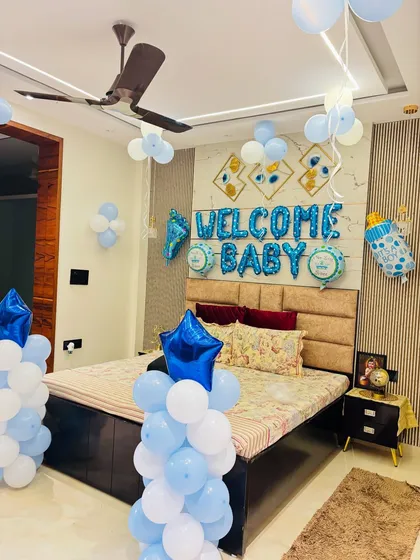 A 'Welcome Baby' room decoration in blue and white, with balloon pillars and decorations over the bed.