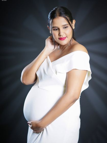 A delicate and thoughtful close-up portrait. The focus is on the mother-to-be's serene expression as she looks down, creating a feeling of quiet anticipation.
