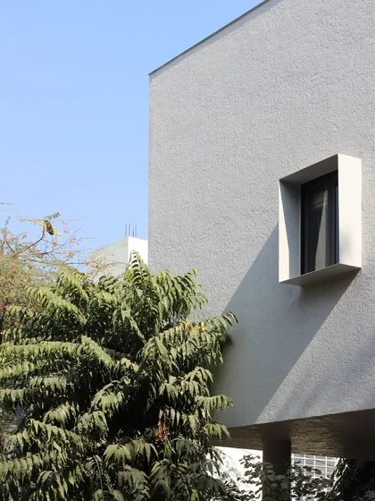A detail of the minimalist facade of the Jaipur House, showing the clean lines of a punched window. This simple gesture creates a strong graphic composition against the textured white wall.