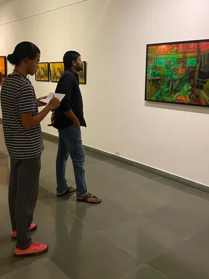 Visitors at the solo show of Sandeep T K, 'Toy Boy From Malabar', observing one of the large photographic prints.