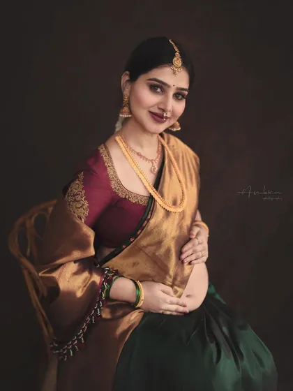 A duplicate of image 71, this portrait is a celebration of Indian heritage, featuring a mother-to-be in a stunning Kanjeevaram silk saree with intricate blouse embroidery. The warm, moody lighting and classic pose create a timeless, painterly effect.