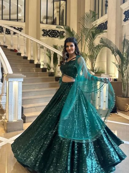 A client enjoying the movement of her green sequined lehenga on a grand staircase. The color and sparkle are truly eye-catching.