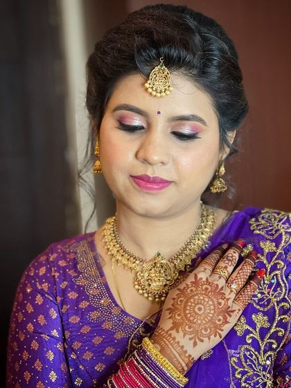 A close-up of Sheela's engagement makeup. The look features soft pink eyeshadow, a matching lip, and beautiful henna details.