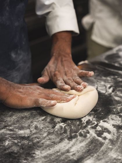 The first step in our artisanal process. Our baker's hands gently knead the dough, starting a journey that ends with the perfect pizza crust or loaf of bread.