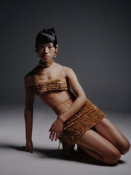 A dynamic, kneeling pose that showcases the full golden outfit. This composition is artistic and editorial, creating a memorable image.