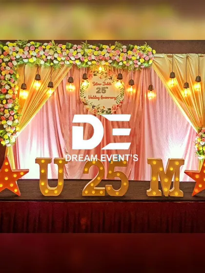 Anniversaries are milestones of love that deserve a special celebration. This cozy and elegant stage for a 25th wedding anniversary features warm draped fabrics, vintage-style lighting, and custom marquee letters to create a romantic atmosphere.