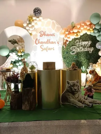 A realistic safari theme featuring lifelike tiger and lion cutouts. The setup combines a grass floor, gold pedestals, and a mix of green and animal-print balloons.