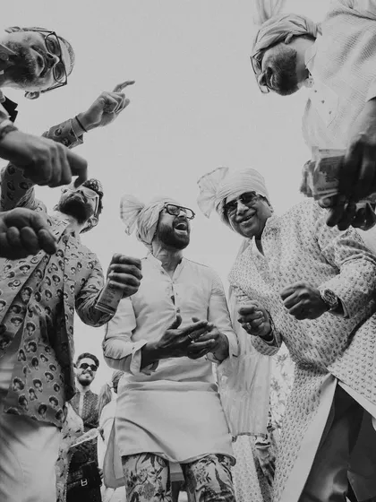 A black and white shot of the groom and his friends dancing with abandon. These are the candid, high-energy moments that truly define a celebration.
