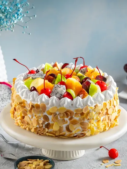 A classic fresh fruit cake with whipped cream and almond flakes, styled with a light and cheerful background to create a perfect e-commerce image for Bakingo.