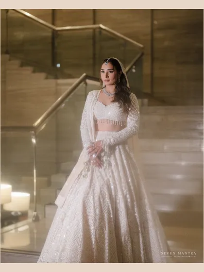 An angel in white. I styled this bride in a stunning all-white chikankari lehenga, creating a look of pure elegance and grace. The soft lighting and modern staircase add to the ethereal, contemporary feel.