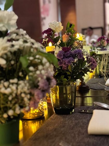A close-up of our minimal yet elegant table decor, featuring fresh floral arrangements in green vases and soft candlelight.
