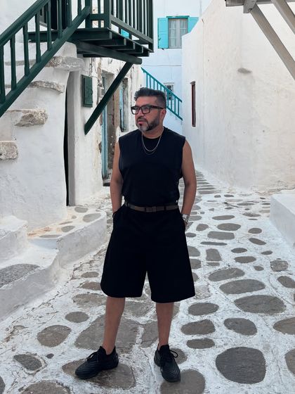 Wandering the iconic white alleys of Mykonos. My all-black sleeveless look contrasts sharply with the backdrop, creating a minimalist yet powerful style statement.