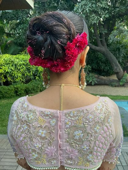 A close-up of the intricate high bun, showing the texture of the hair and the vibrant red flowers.