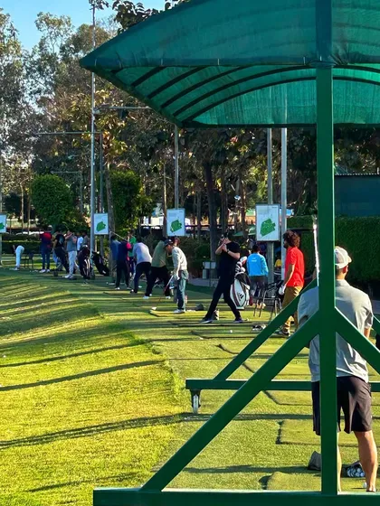 A packed driving range on the weekend, with every bay filled with enthusiastic golfers.