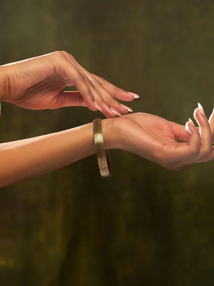 A close-up on the hands and bracelets from the JJ Valaya x Aulerth jewelry collaboration, capturing the intricate design and finish of the pieces.