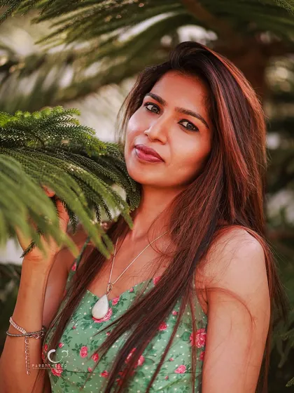 A gentle and engaging pose, interacting with the natural elements. Her soft smile and the way she holds the branch create a serene and peaceful mood.