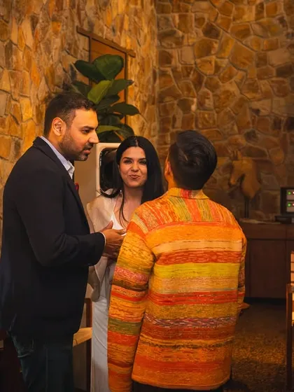 Guests engage in conversation during the Soho House event inside our Pavilion. The warm interior with its stone wall and DJ setup creates a sophisticated and relaxed party atmosphere.