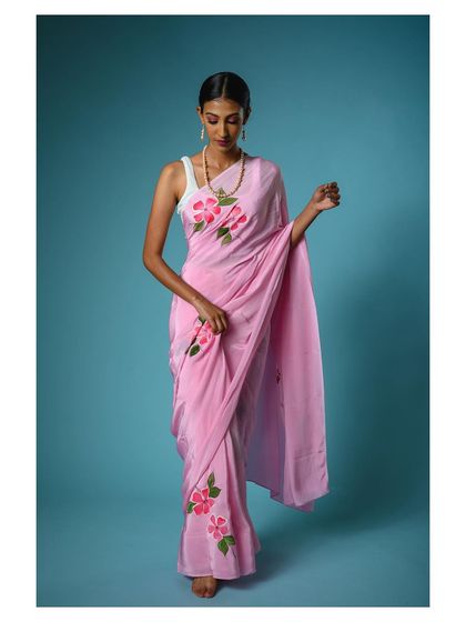 A full-length shot of the pink floral saree, showing how it can be styled with a modern white tank top. This demonstrates the versatility of the garment for a contemporary audience.