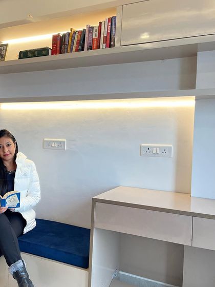 A personal shot of me enjoying the compact study nook we designed. This space combines a bench seat with a sleek desk and shelving, proving that functional design can also be cozy and inviting.