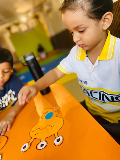 Two boys work together at the table, sharing the creative space while focused on their individual projects.