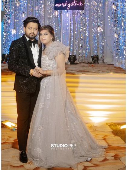 A stylish portrait of Nikhil and Srishti against a glittering, modern backdrop. Their formal attire and confident pose reflect the chic, celebratory vibe of their engagement.