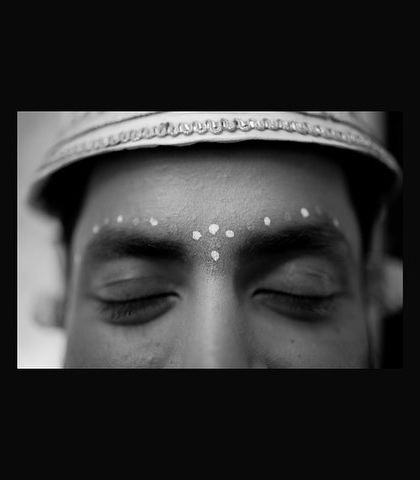 An artistic close-up of a Bengali groom's eyes, adorned with traditional sandalwood paste dots. A powerful black and white shot focusing on cultural details.
