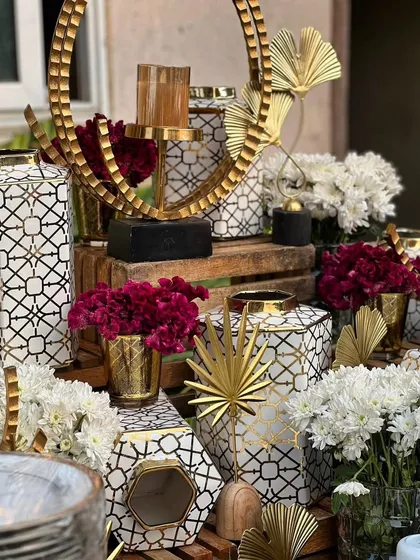 Elegant and glittering decor for a festive party, featuring white and gold geometric vases and candle holders.