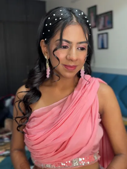 This client is channeling a modern goddess vibe. The look features a trendy pearl headband, soft pink makeup, and a draped, one-shoulder outfit.