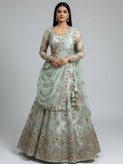 This image shows the intricate floral embroidery in shades of pink and gold that adorns the mint green lehenga, making it a work of art.