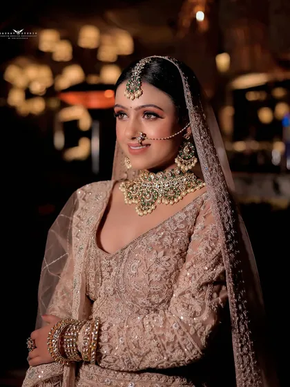 A soft, elegant portrait of a bride in a pastel pink lehenga, with beautiful bokeh in the background.