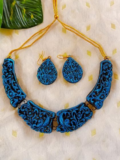 This carved 'hansli' necklace is finished in a stunning metallic blue, which highlights the depth of the hand-carved patterns.