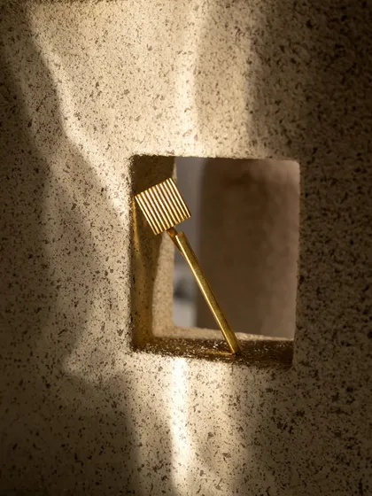 A creative product shot of a hair accessory, viewed through a hole in a textured block. This artistic framing draws the eye directly to the product and creates a memorable image.
