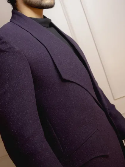 A close-up of the fabric and cut of the wine-colored tuxedo. The rich texture of the material and the unconventional lapel design are what make this piece stand out.