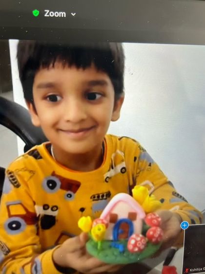A young student is all smiles with the fairy house he created during our live online clay workshop.