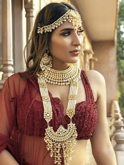 A modern take on bridal jewellery, this model wears a layered pearl and Polki set with a contemporary red blouse. This shows how traditional jewellery can be styled in new ways.
