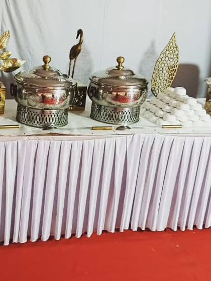 A simple and clean buffet setup on a red carpet for an event of 70 guests in Palam Vihar. The white table skirting provides a classic and neat look.
