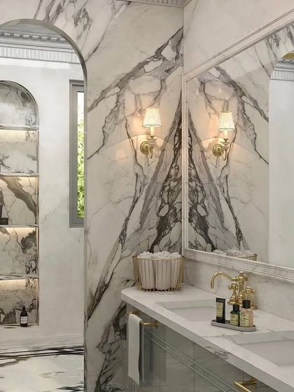 Marble's dramatic veining instantly invites opulence into a space. Here, I used book-matched marble slabs to create a stunning, symmetrical feature wall behind the vanity, complemented by classic gold fixtures and sconces.