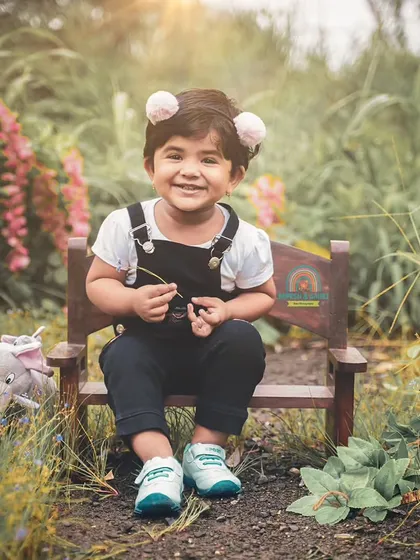 A happy smile from a little girl during her outdoor photoshoot. We bring props like this little bench to create cute and comfortable poses even in a park.