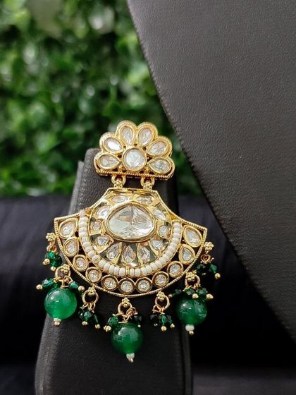 A classic chaand bali earring with green beads and a floral kundan top.