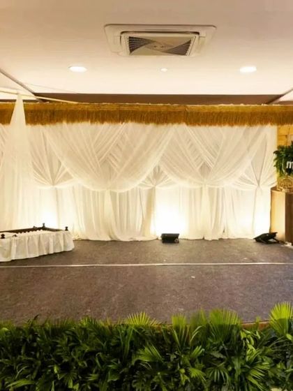 For a minimalist and modern naming ceremony, I created this clean stage design. It uses soft white fabric drapes for the backdrop and a simple wooden sign, creating a calm and sophisticated ambiance.