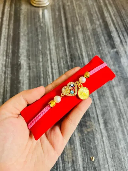 This adjustable friendship band doubles as a beautiful rakhi. It features an evil eye heart charm and a coin charm on a colorful thread.