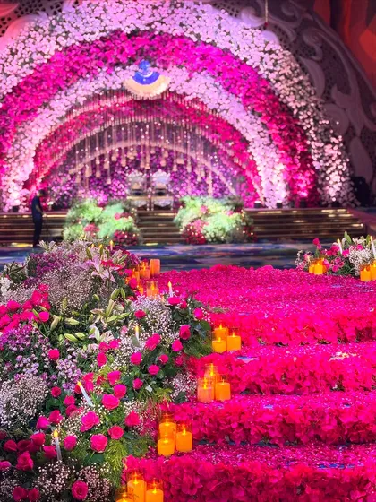 Welcome to 'Rani Bagh', or the Queen's Garden. This design features a massive floral archway in cascading shades of pink, leading to a stage covered in a carpet of petals and lit by countless candles, fit for royalty.