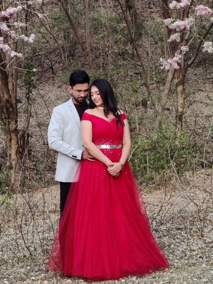 An intimate moment in a beautiful woodland setting. This off-shoulder red gown with a sparkling belt is both romantic and elegant for a pre-wedding photoshoot.