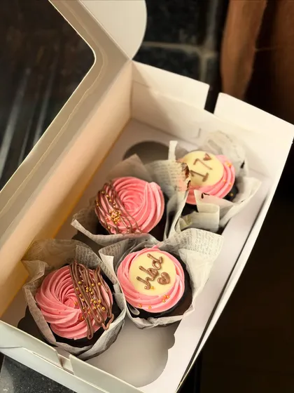 Simple and pretty pink swirl cupcakes. Some have "HBD" toppers and others are drizzled with chocolate and finished with gold sprinkles for a festive touch.