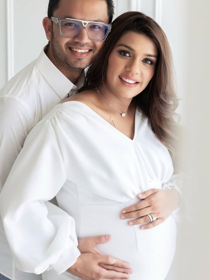 A classic maternity portrait where the couple is looking at the camera. The all-white styling and background create a timeless look that will be cherished for years to come.