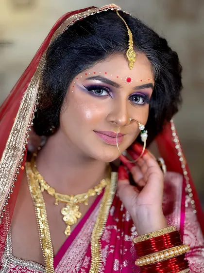 This image captures the sharp, winged eyeliner and the beautiful blend of colors on the eyes, a signature of the Bengali bridal style.