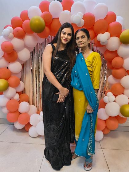 A client celebrating with her mother, looking stunning in a classic black sequin saree. This timeless piece is perfect for any celebration.