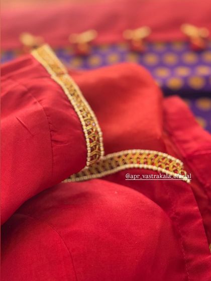A close-up of the delicate pearl edging on the neckline of a red silk blouse.
