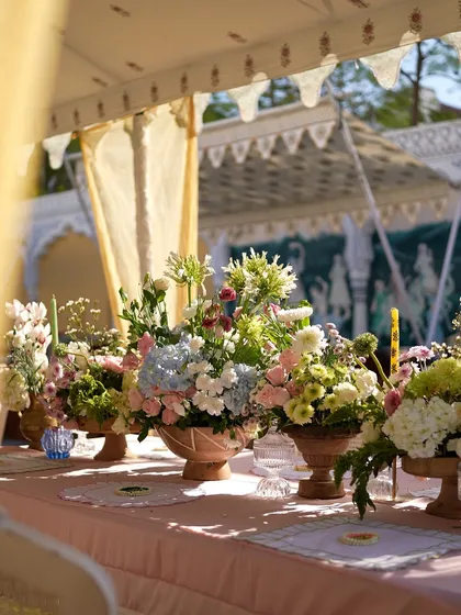 A variety of floral centerpieces lined a long table at this pastel-themed Mehendi. Each arrangement was unique but tied together by a soft color palette of pink, blue, and white.